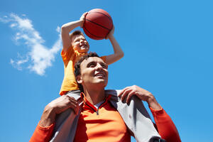 Image of young man and his son playing basketball