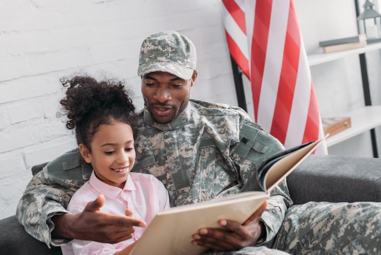 Male soldier reading book to his daughter