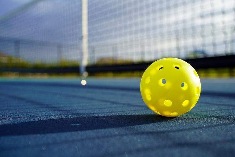 Close up of a pickleball on a pickleball court.